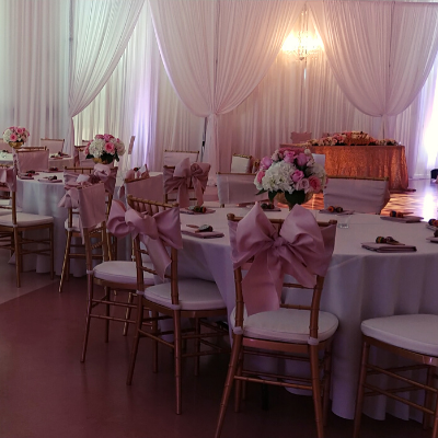 Dinner tables with pink bows on chairs