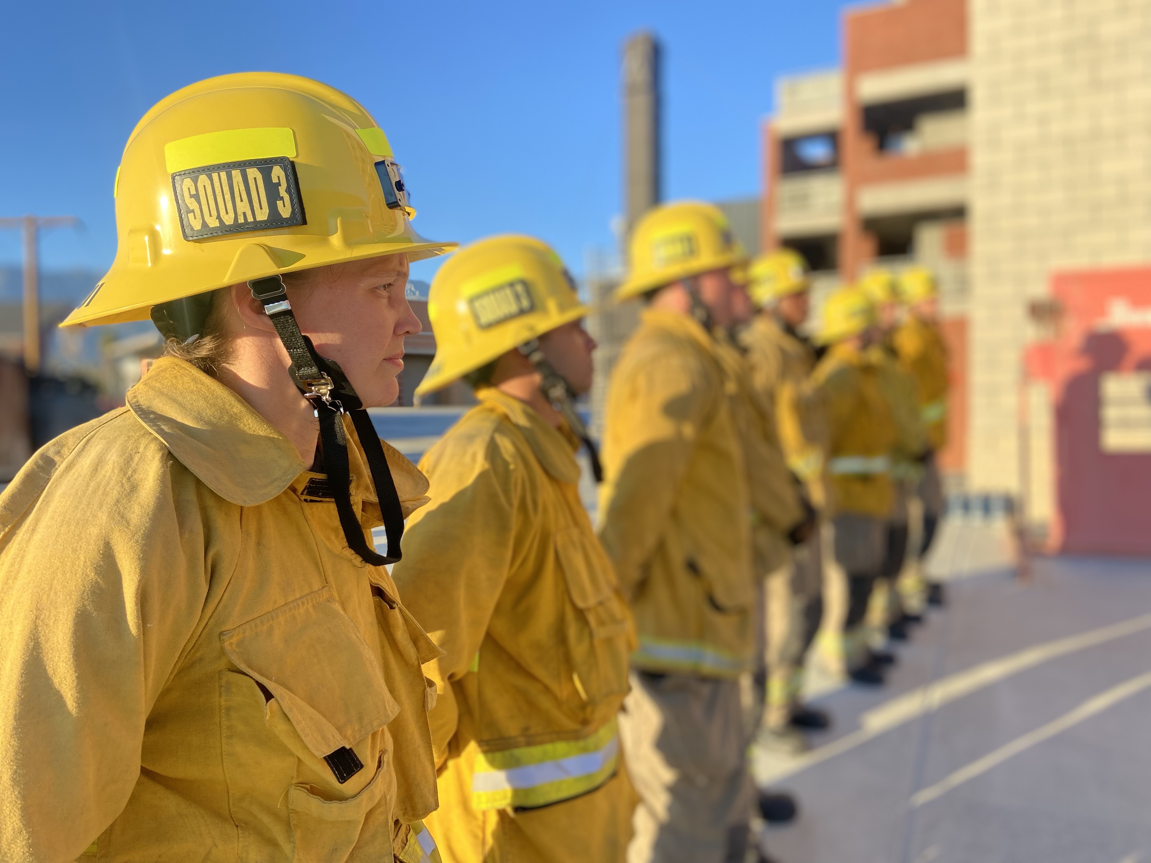 Firefighter recruits standing at attention waiting for further instruction from their teacher