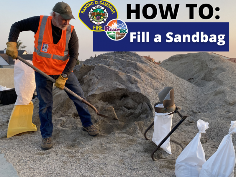 Volunteer in vest with shovel filling sandbag