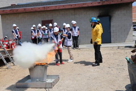Jr. Firefighter Campers extinguishing a simulated trash can fire using a fire extinguisher