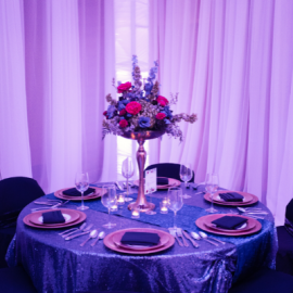 Round table with tall flower vase and formal place settings