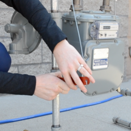 Person using two hands to turn off a natural gas meter