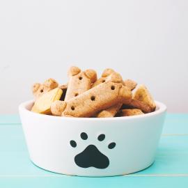 Picture of dog bones in a white bowl with a black dog paw on the bowl