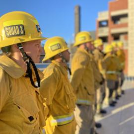 Firefighter recruits standing at attention waiting for further instruction from their teacher