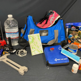 Emergency Preparedness Kit items laid out including a jug of water, tools, medication, first aid kit, duffle bag, and running shoes